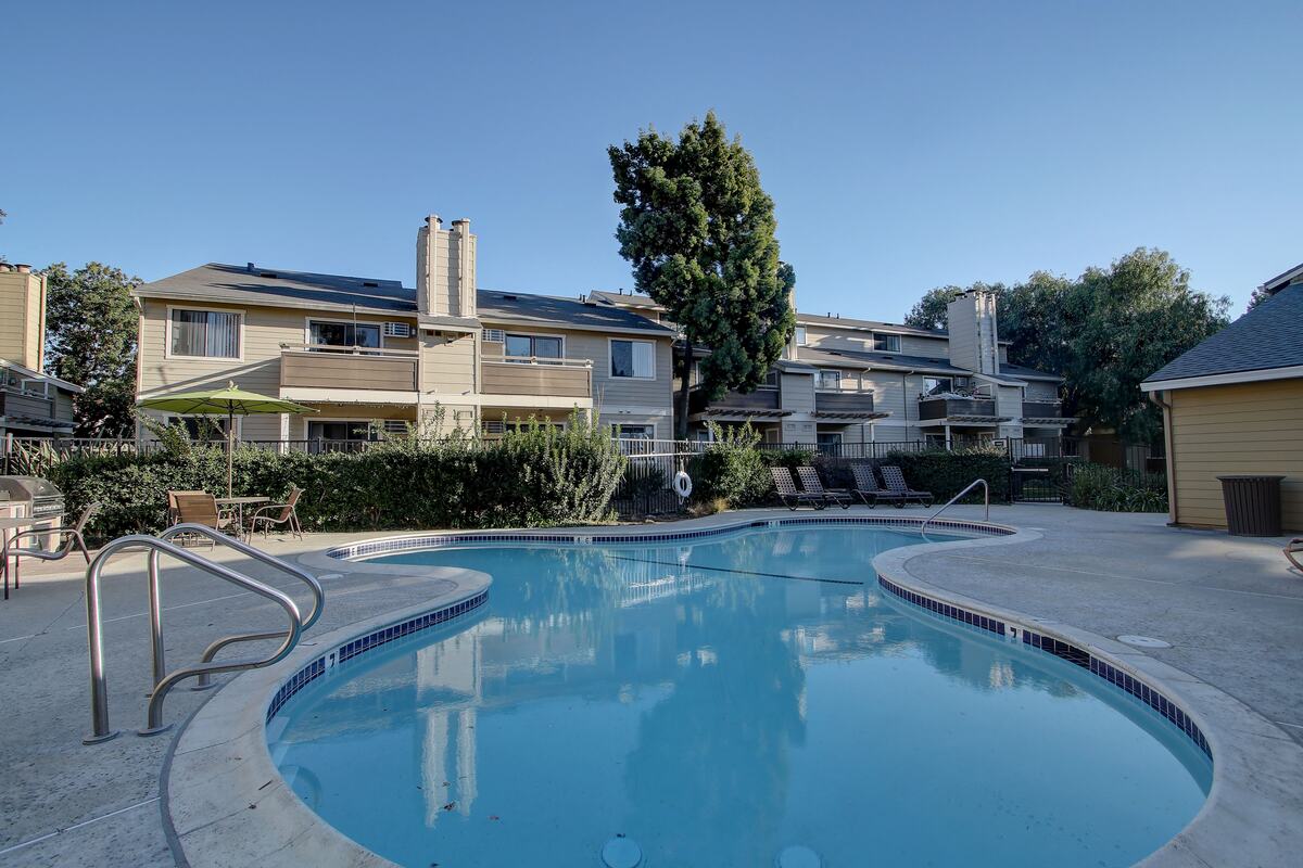 Apartment community swimming pool ringed by low buildings and trees