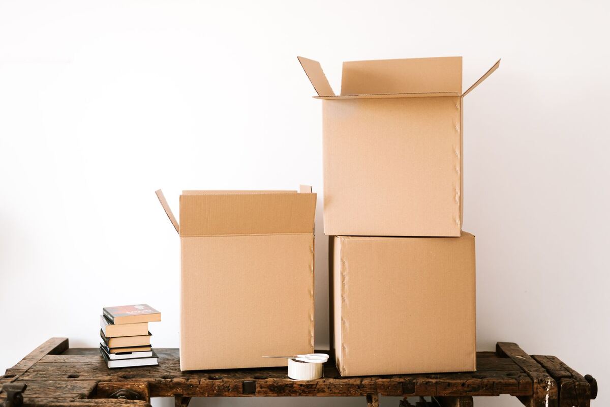 Cardboard boxes and a stack of books on a wooden bench