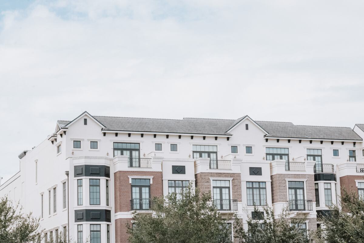 Brick and white apartment block with gabled roofs under a pale sky