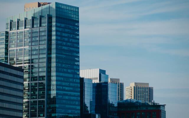 Glass office towers rising against a pale daytime sky