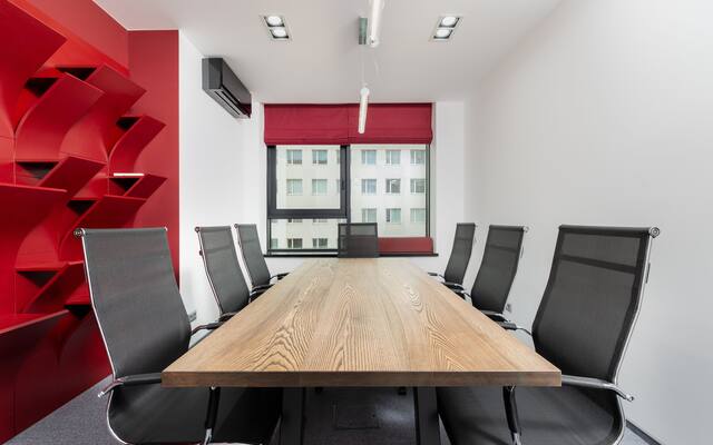 Empty meeting room with a long wooden table and mesh chairs