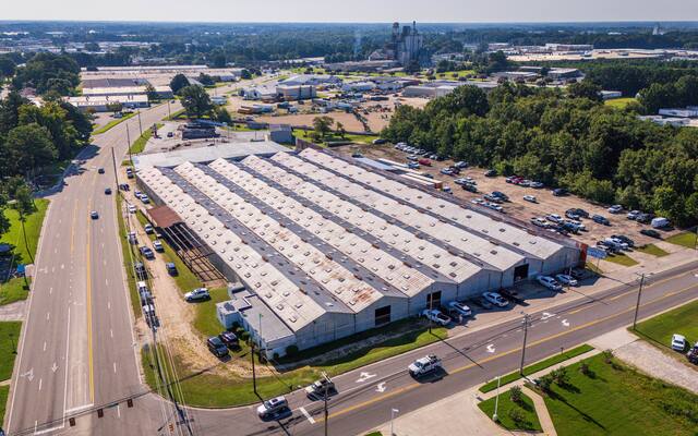 Aerial view of long warehouse buildings beside a divided road