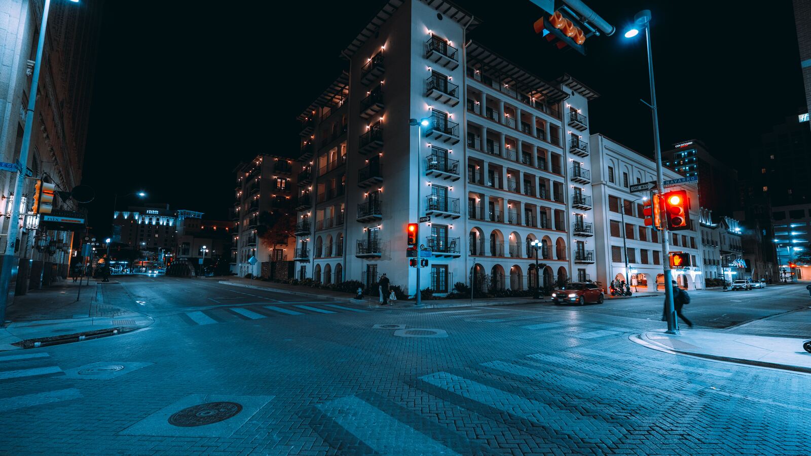Balconied mid-rise building at a quiet downtown San Antonio crossing at night