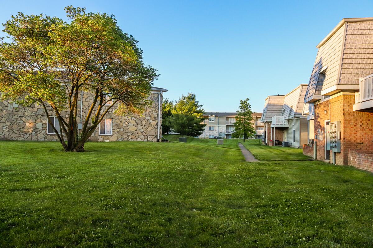 Two-storey garden apartment buildings around an open lawn and a shade tree