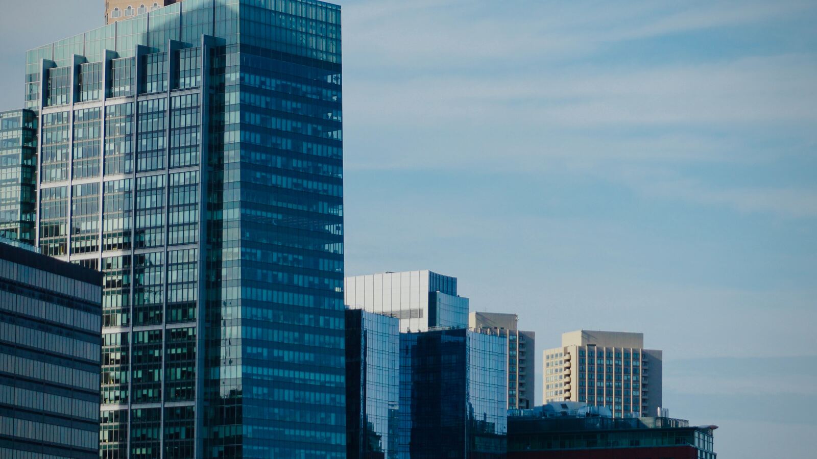 Glass office towers rising against a pale daytime sky