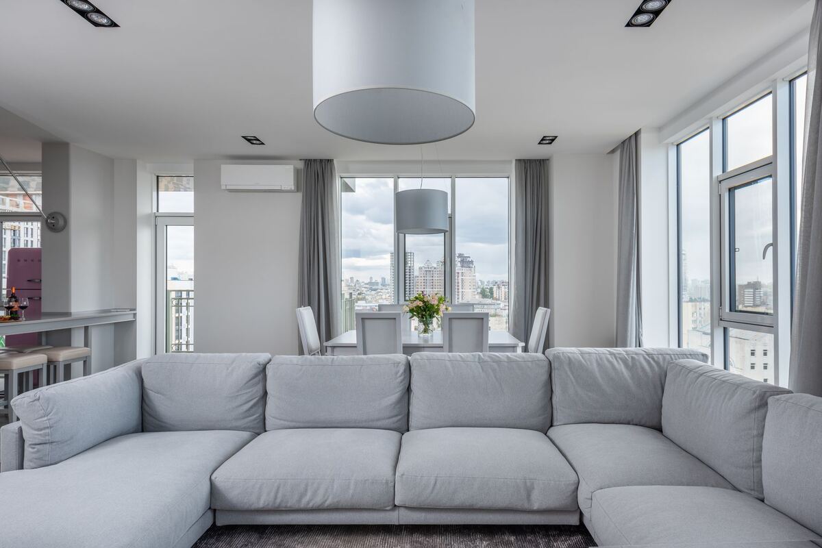 Bright living room with a sectional sofa and floor-to-ceiling city windows