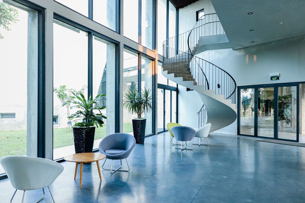 Glass-walled lobby with a spiral staircase and lounge chairs