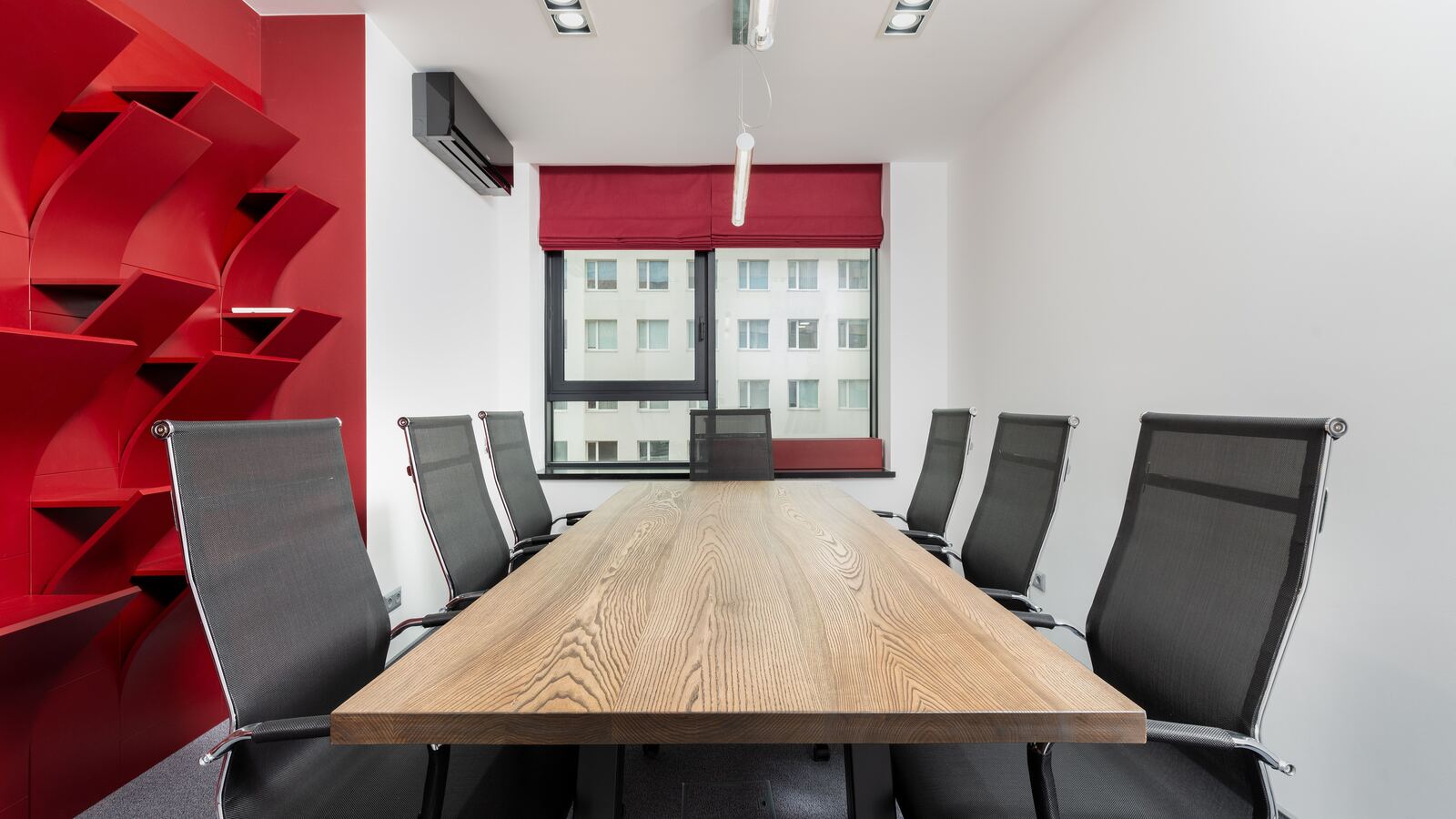 Empty meeting room with a long wooden table and mesh chairs