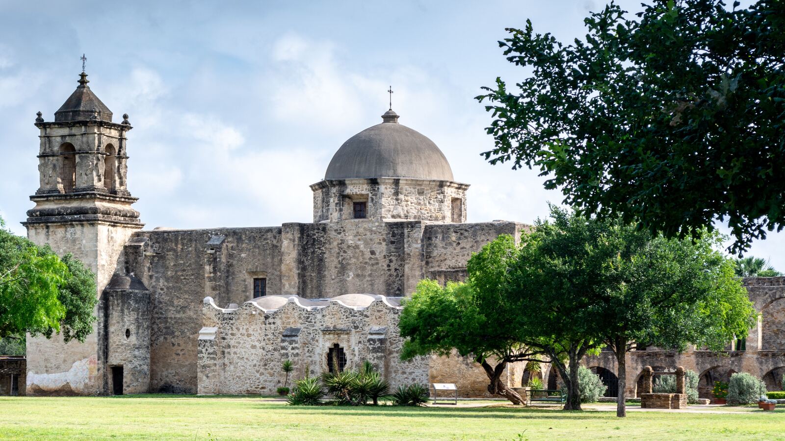 The dome and bell tower of Mission San Jose above its lawn on the San Antonio south side