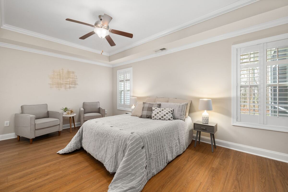 Furnished bedroom with grey bedding and shuttered windows